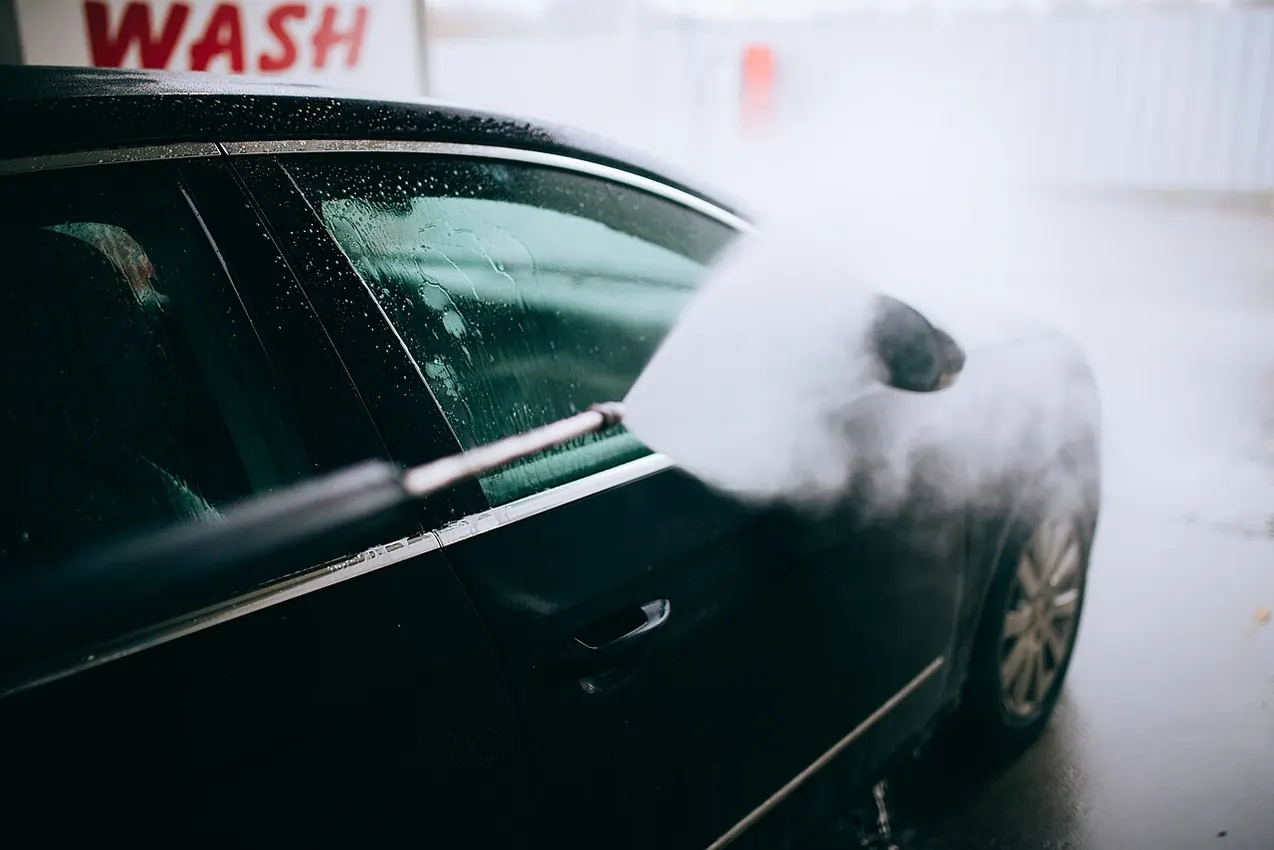Black vehicle being cleaned with high-pressure water spray