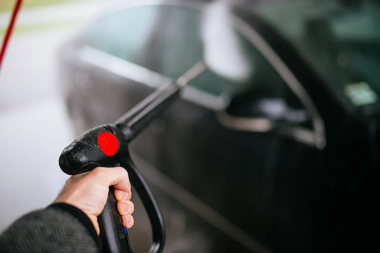 Pressure washer cleaning the exterior of a black vehicle